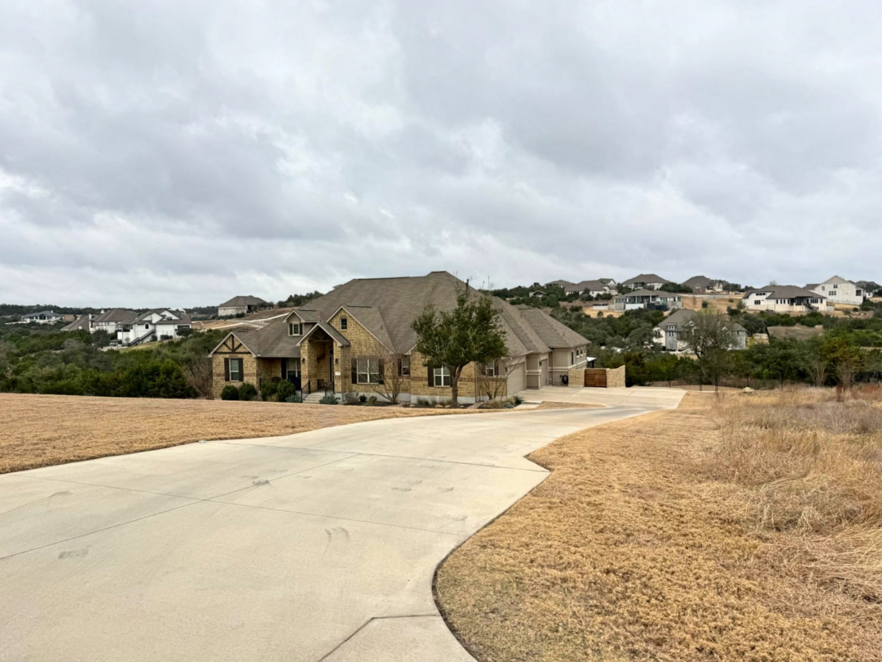 Saratoga Hills Austin TX 78737 luxury home below street with Hill Country neighborhood views