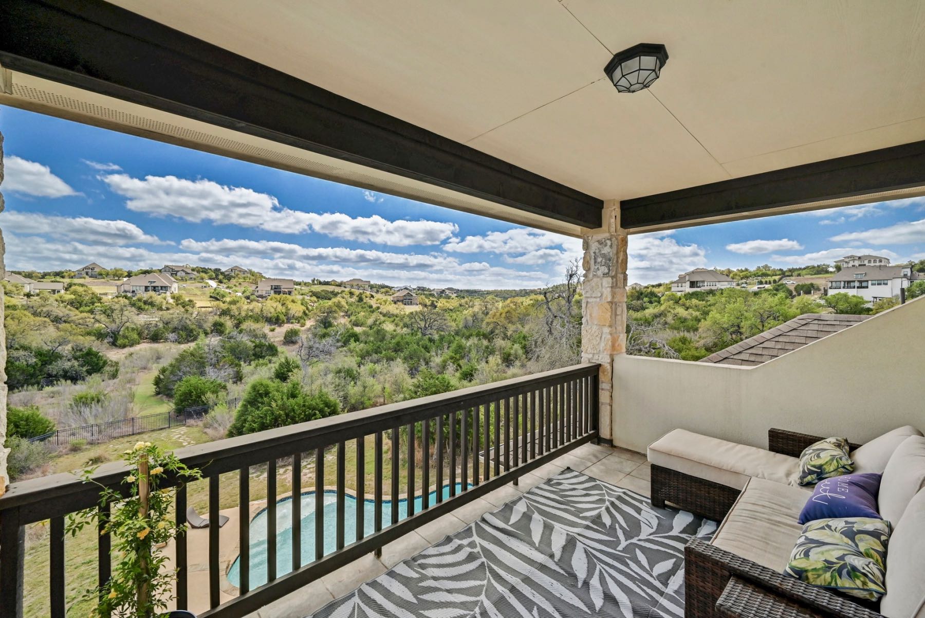 Covered outdoor balcony with pool and greenbelt views at an Austin Texas home