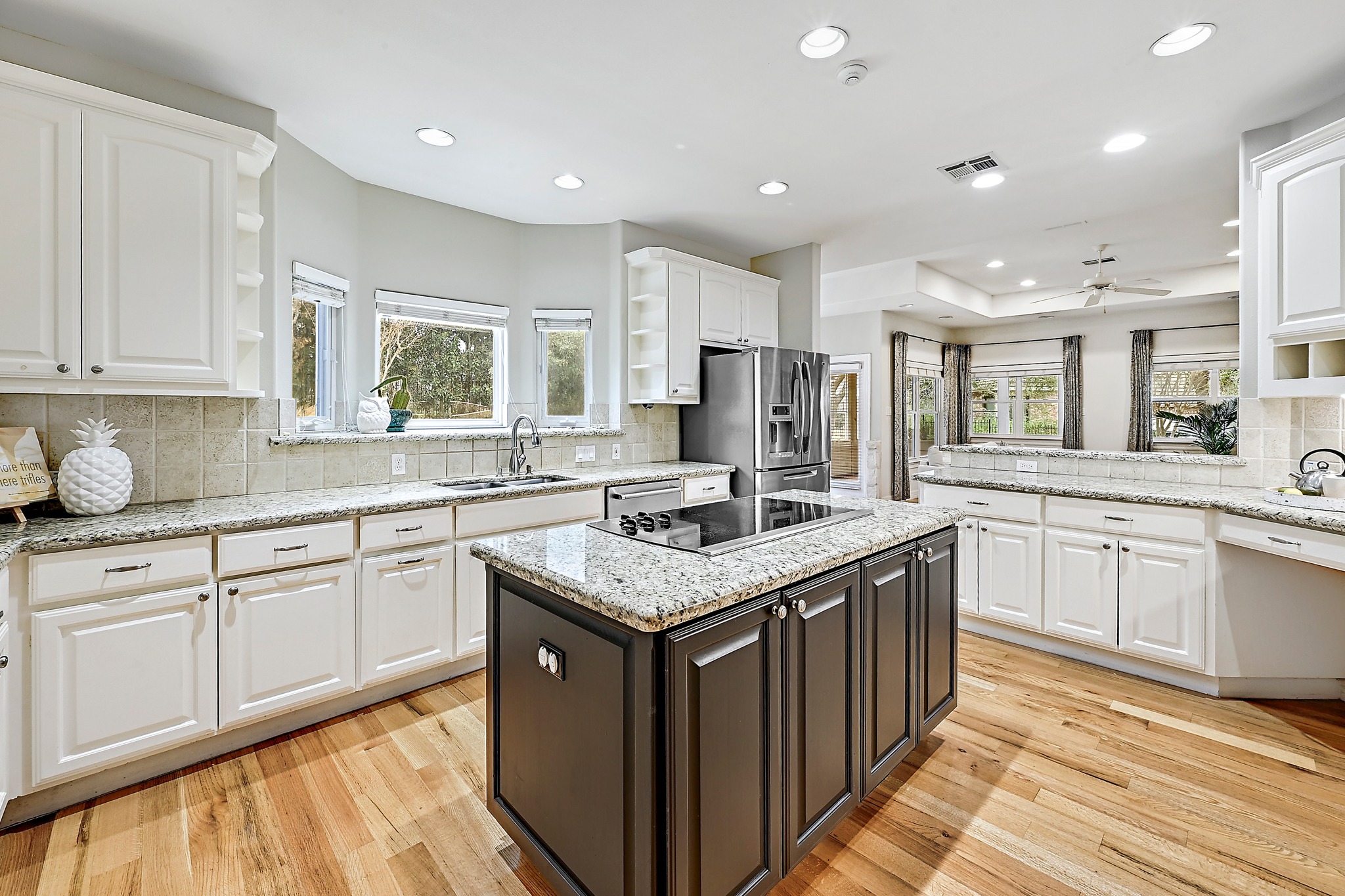 Gourmet kitchen at 22 Hedgebrook Way with white cabinets, granite countertops, dark island with cooktop, and stainless steel appliances