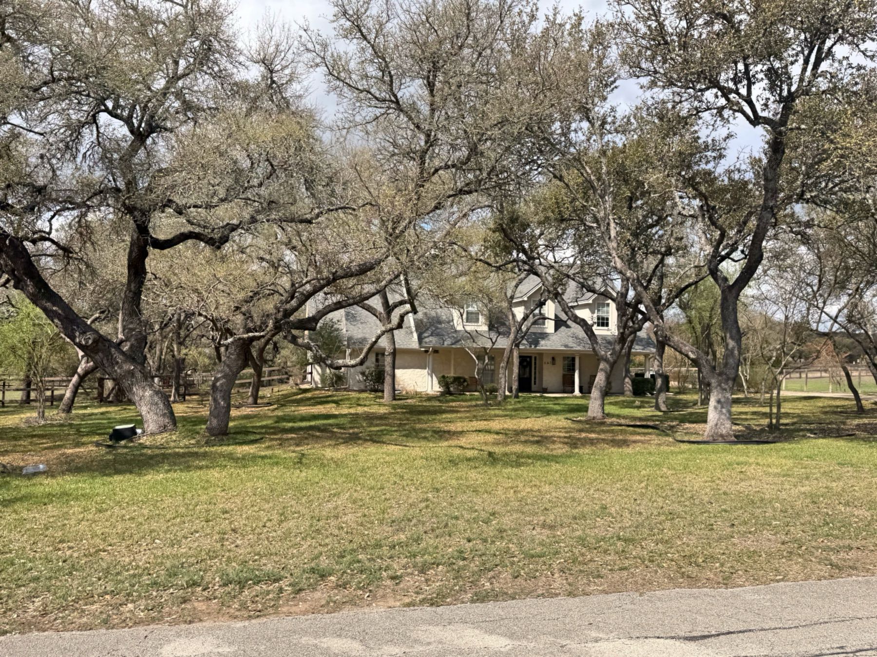 Home nestled among mature live oak trees in Hidden Springs Ranch Dripping Springs TX 78620
