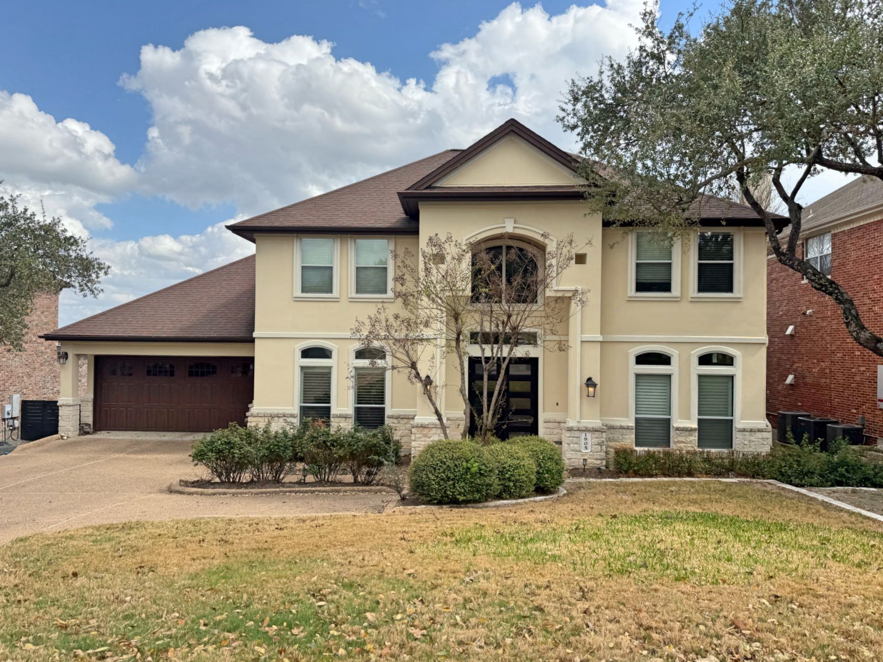 Two-story stucco and stone home with two-car garage and arched windows in Lake Pointe Austin TX 78738
