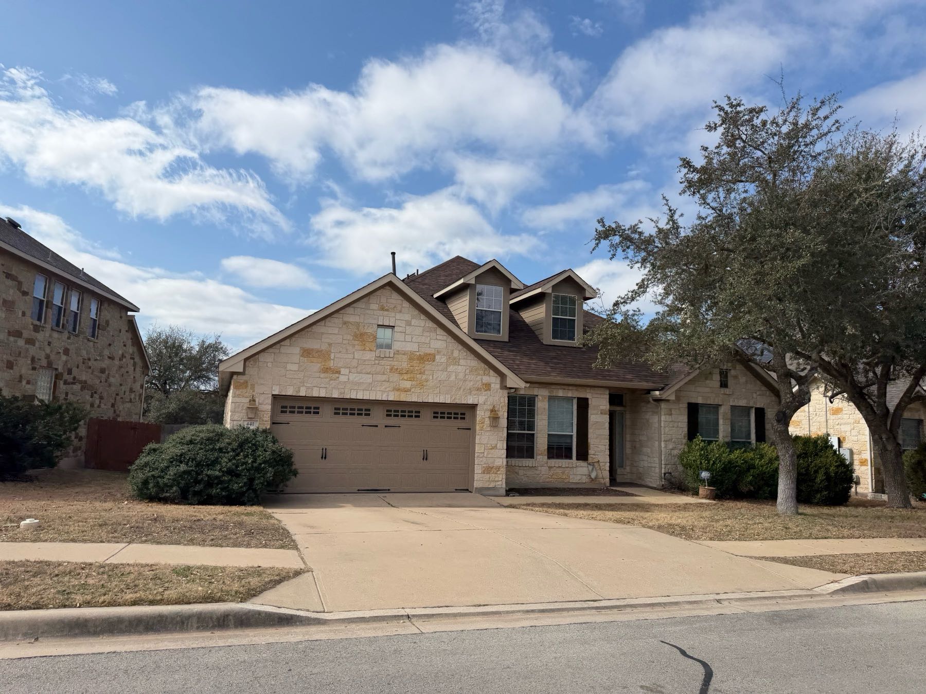 Stone home with wide driveway and two-car garage in Ledge Stone, Austin TX