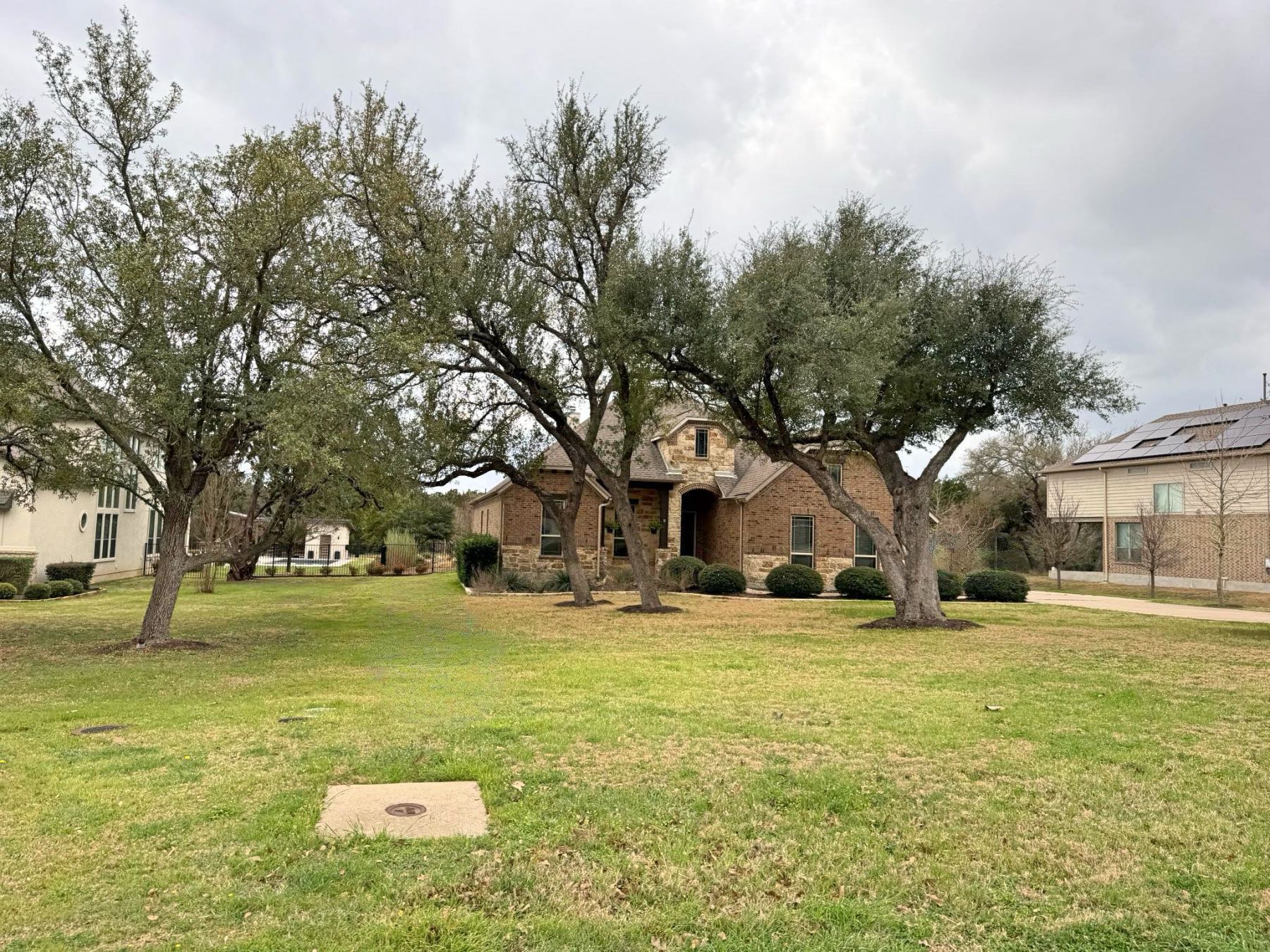 Stone home with mature live oaks and manicured lawn in Rim Rock Driftwood TX 78619