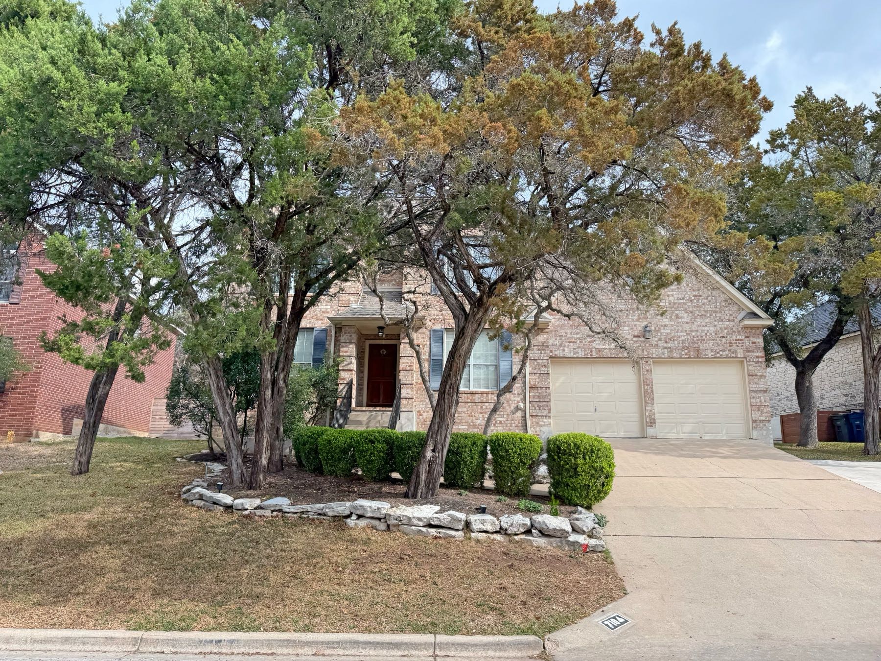 Two story brick home elevated above street with rock landscaping in Great Hills Austin TX 78759