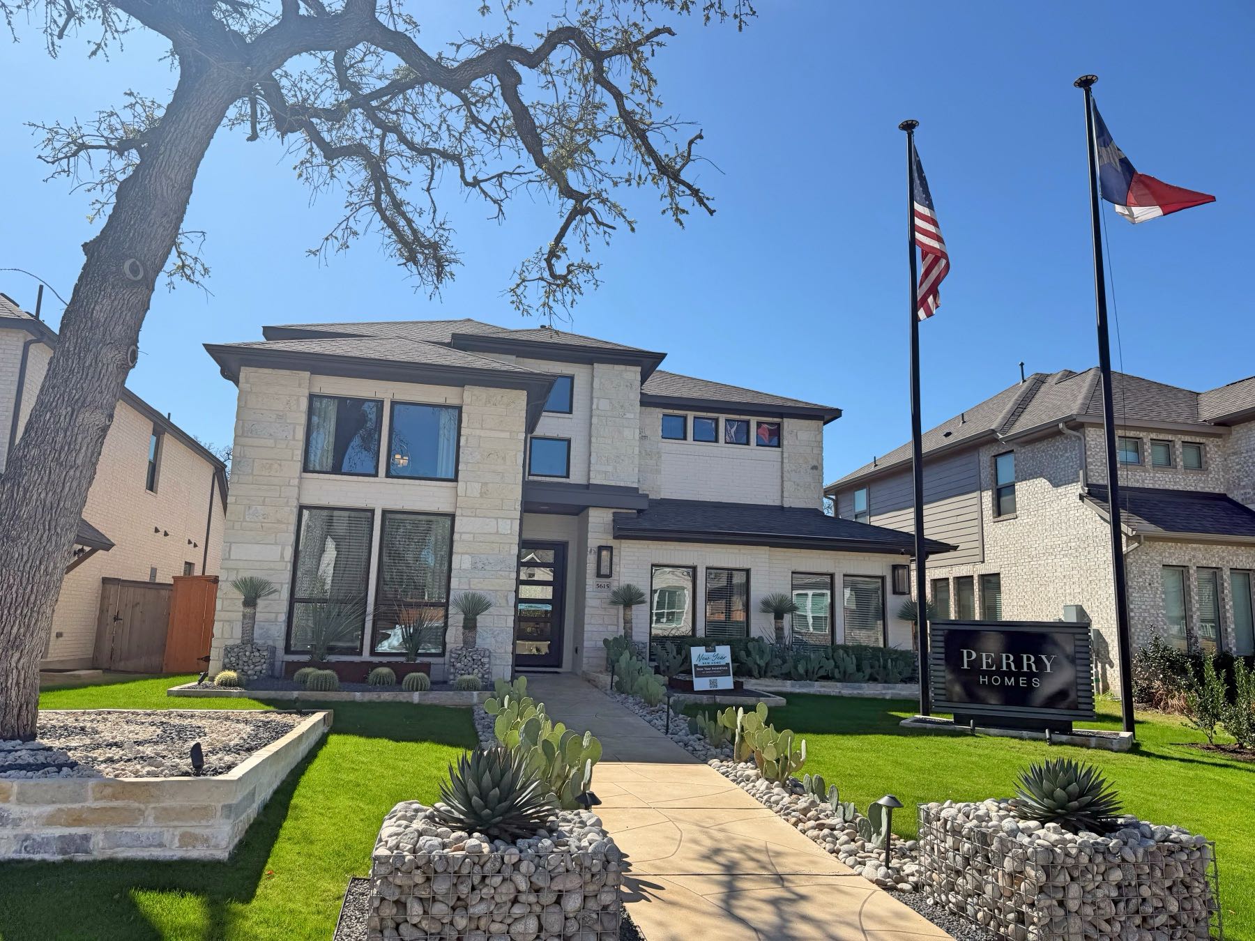 Perry Homes model home with limestone stone exterior, manicured landscaping, and American and Texas flags in Parkside Peninsula, Georgetown TX 78628