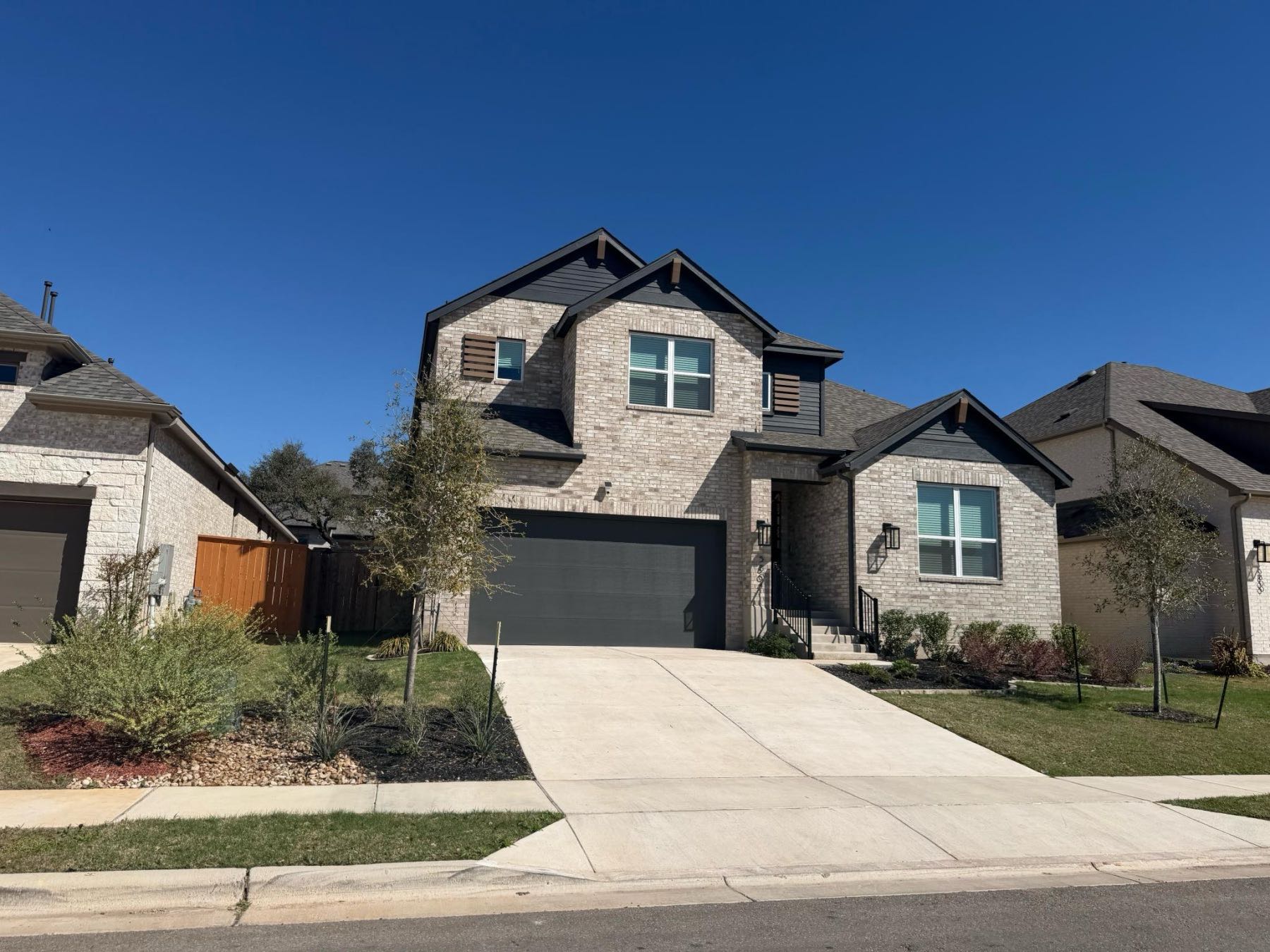 Two-story stone and brick craftsman-style home with single-car garage in Parkside Peninsula, Georgetown TX 78628