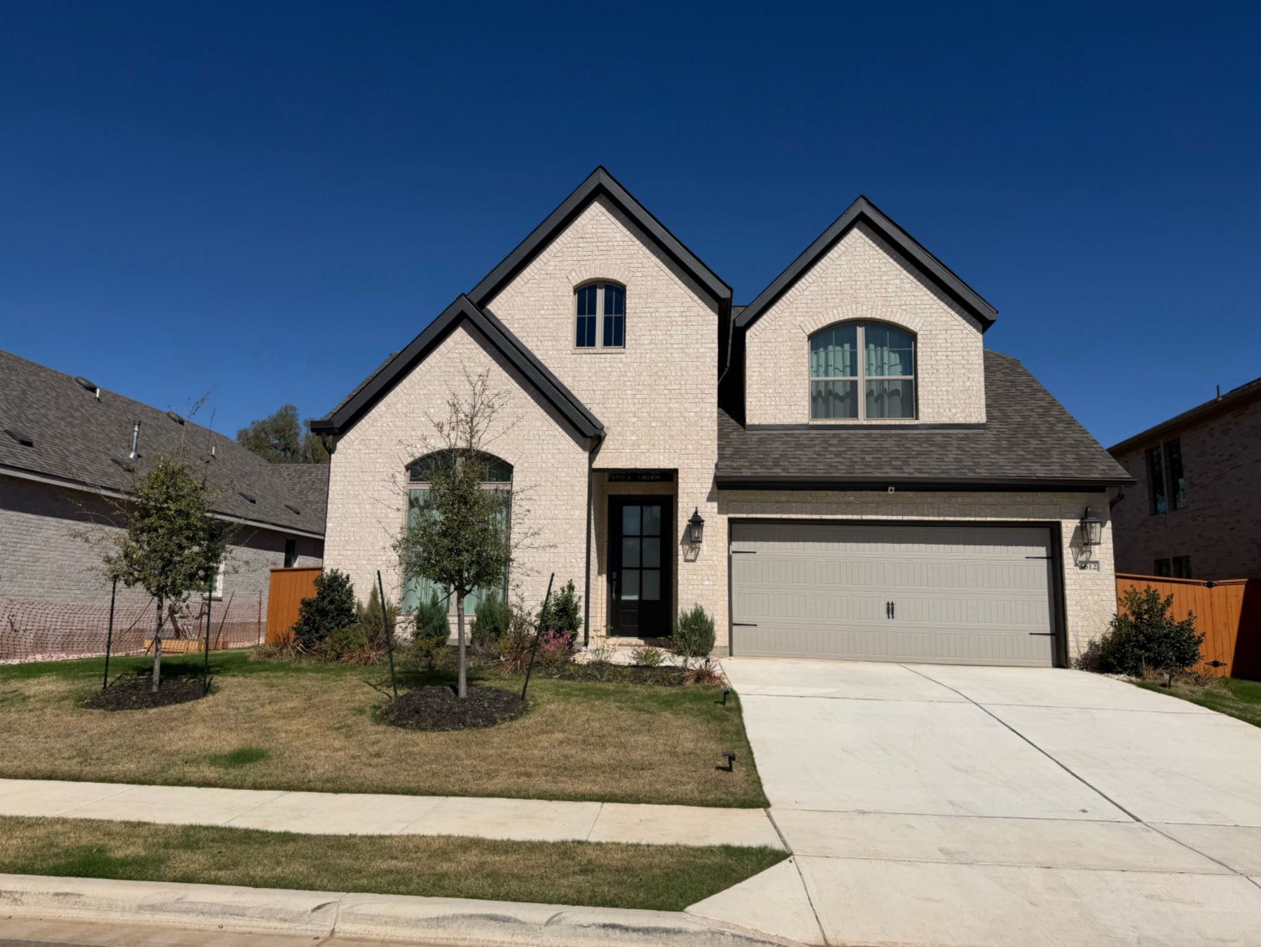 Two-story white brick home with arched window detail and single-car garage in Parkside Peninsula, Georgetown TX 78628