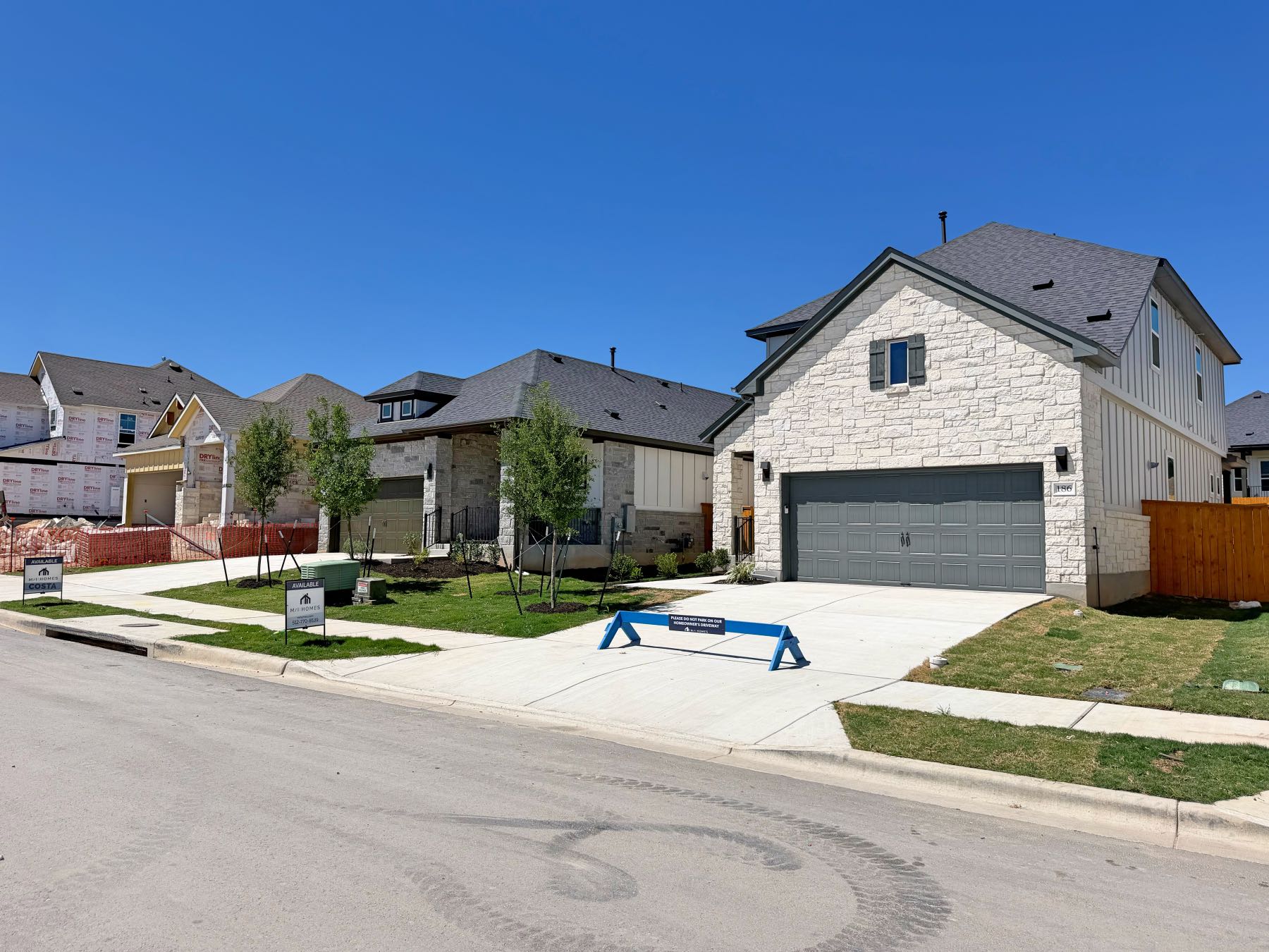 Stone exterior new construction home with two car garage in Heritage neighborhood Dripping Springs Texas