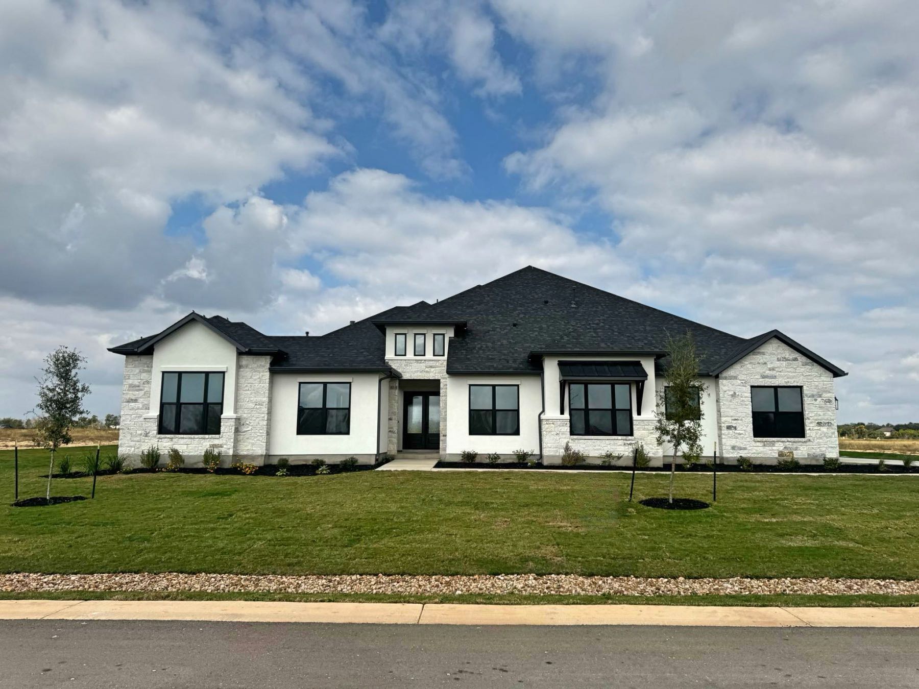 Modern new construction home with white limestone exterior and black windows in Hilltop Ranch Leander TX 78641