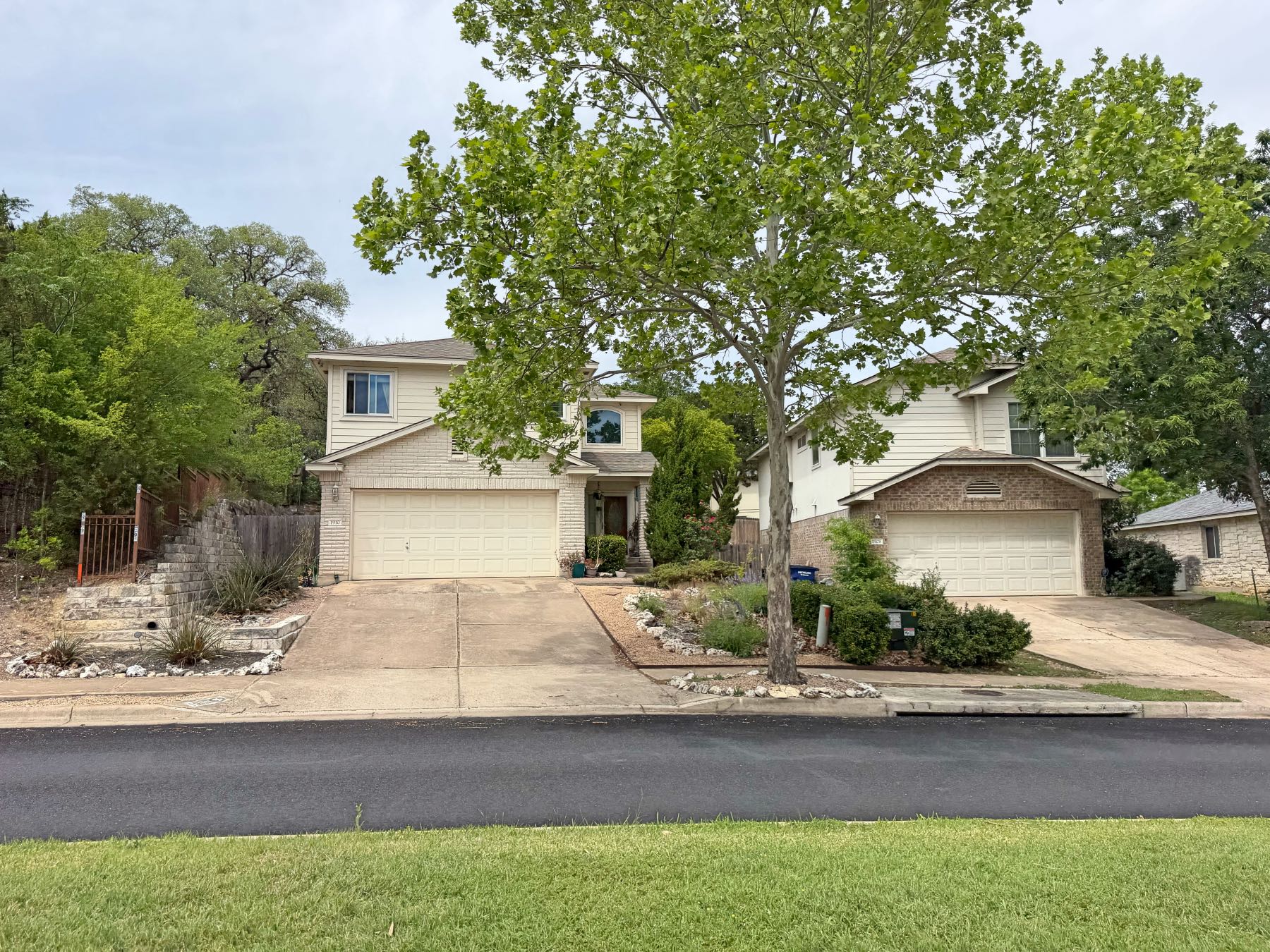 Two story homes with xeriscape rock landscaping and large shade trees in Olympic Heights Austin TX 78748