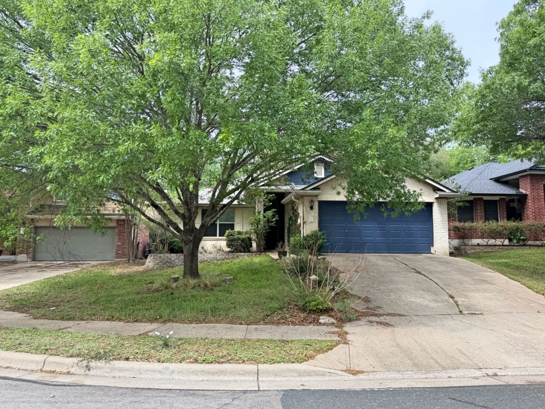 Single story home with distinctive blue garage door on corner lot in Southland Oaks Austin TX 78748