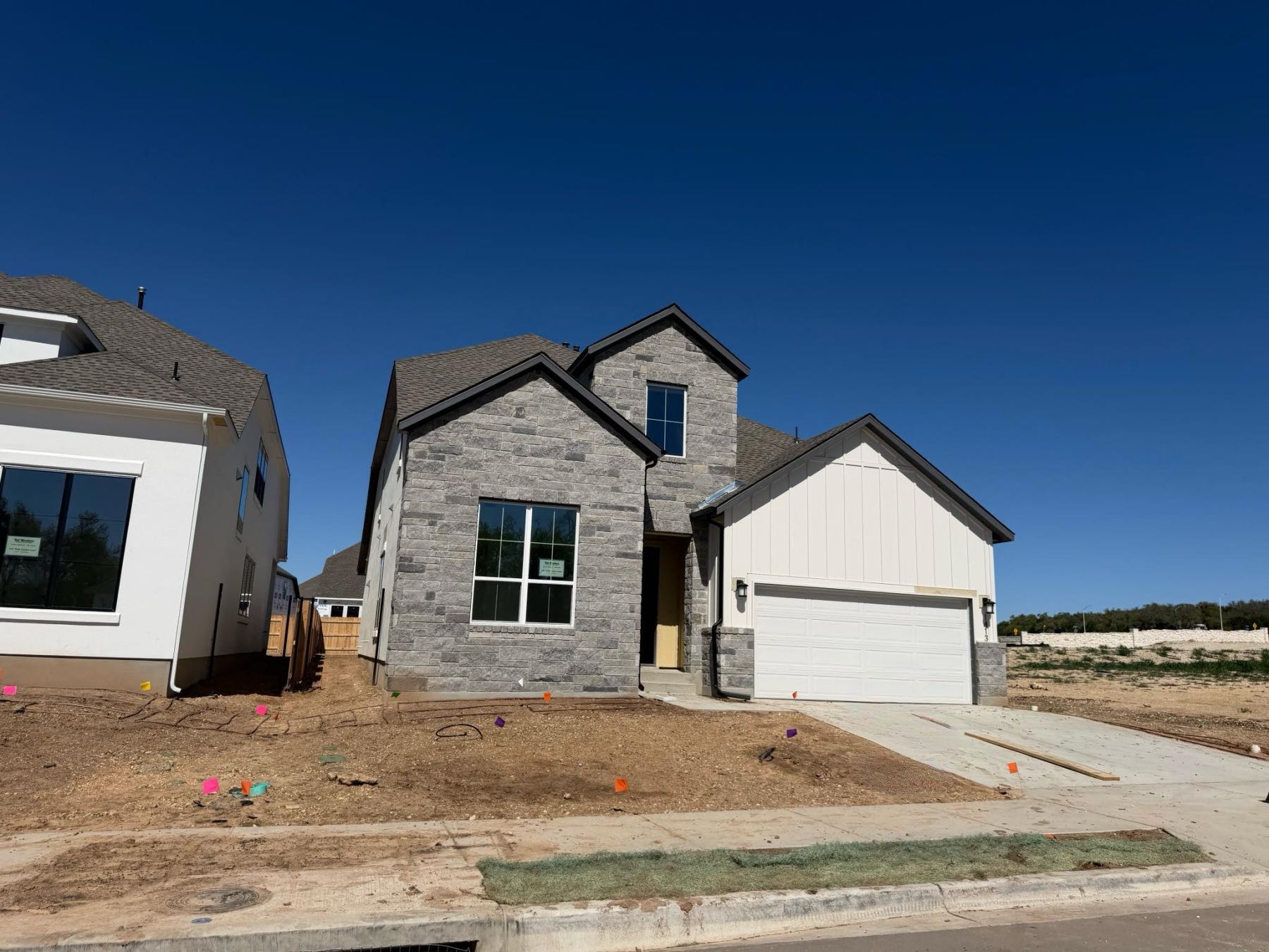 New construction home featuring stone and white board and batten siding with two-car garage in Wildspring Leander TX 78641