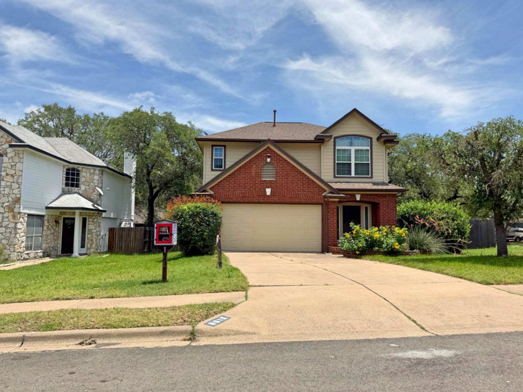 Two-story brick home for sale in Parkwood Austin TX 78748 with yellow flowers in the front yard